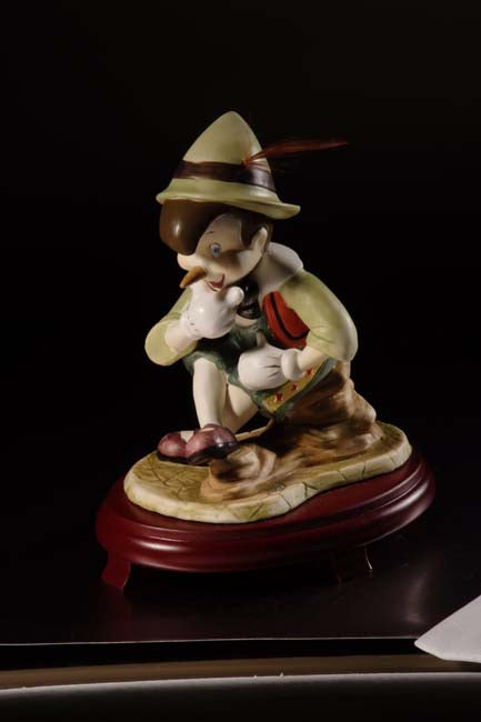 Figura de Pinocho de cerámica sobre centros de mesa con base de madera de cerezo #9D6736