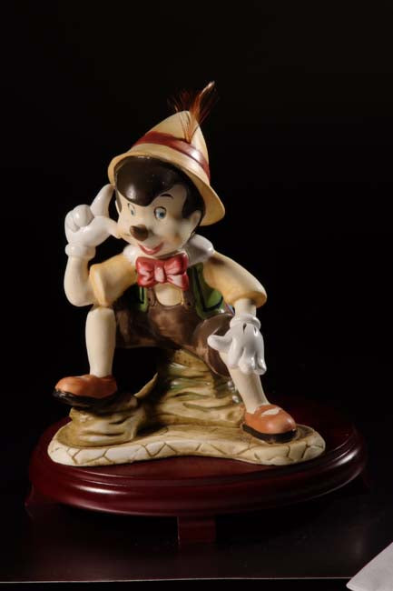 Figurilla de Pinocho de cerámica sobre centros de mesa con base de madera de cerezo #9D6737